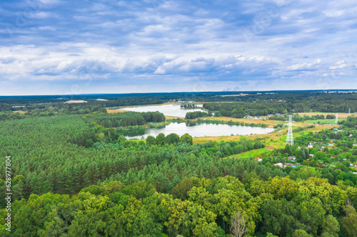 Równina pokryta zielonym lasem. wśród gęstwiny drzew widać dwa jeziora. Niebo jest lekko zachmurzone. Zdjęcie z drona. © boguslavus