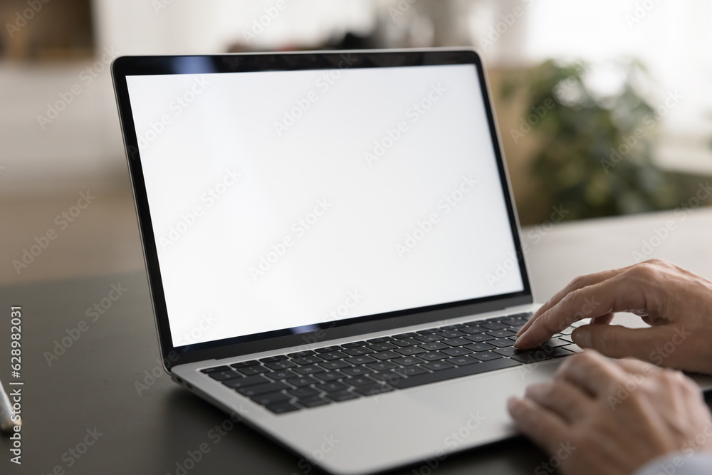 Empty white laptop display on work table of mature business freelance woman. Cropped shot of senior customer lady typing on computer with copy space on blank screen. Cropped close up shot Empty white laptop display on work table of mature business freelance woman. Cropped shot of senior customer lady typing on computer with copy space on blank screen. Cropped close up shot
