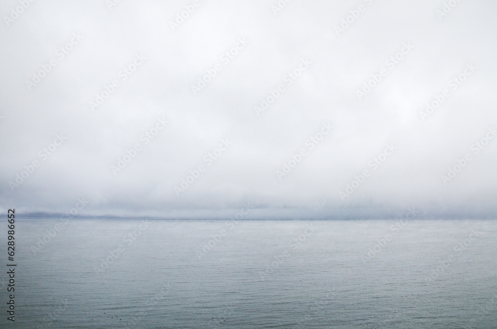 Grey sky before the rain above calm lake water surface. Natural texture or background Grey sky before the rain above calm lake water surface. Natural texture or background