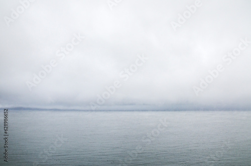 Grey sky before the rain above calm lake water surface. Natural texture or background