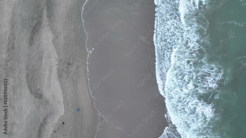 Downward view of waves dissipating into foam on sandy shore aerial vertical angle Downward view of waves dissipating into foam on sandy shore aerial vertical angle