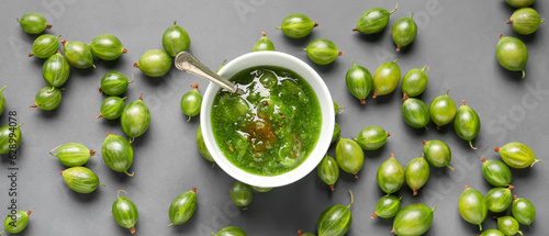 Bowl with tasty gooseberry jam and fresh berries on grey background, top view