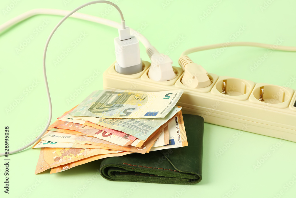 Wallet with money, plugs and power socket on green background. Electricity bill concept Wallet with money, plugs and power socket on green background. Electricity bill concept