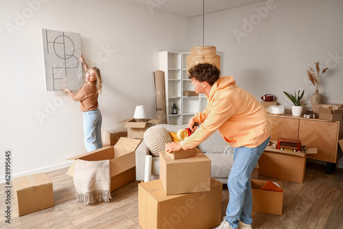Schilderij op canvas Young couple packing things in room on moving day