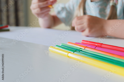 Cute child drawing a picture with colored felt-tip pens. Concept of hobby or education