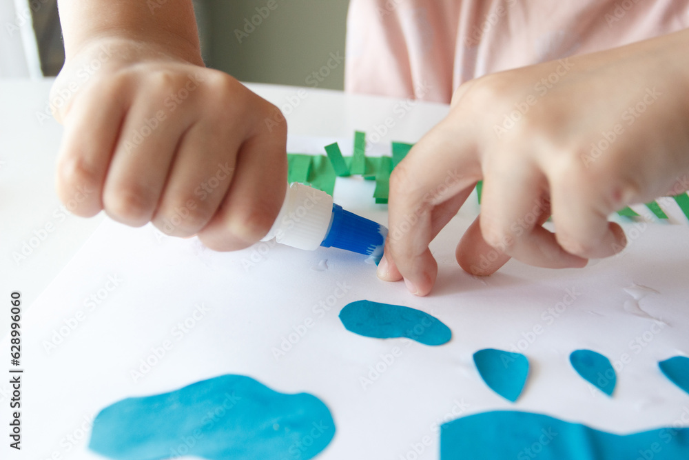 Cute child creating an applique with colored paper and glue. Concept of hobby or education Cute child creating an applique with colored paper and glue. Concept of hobby or education