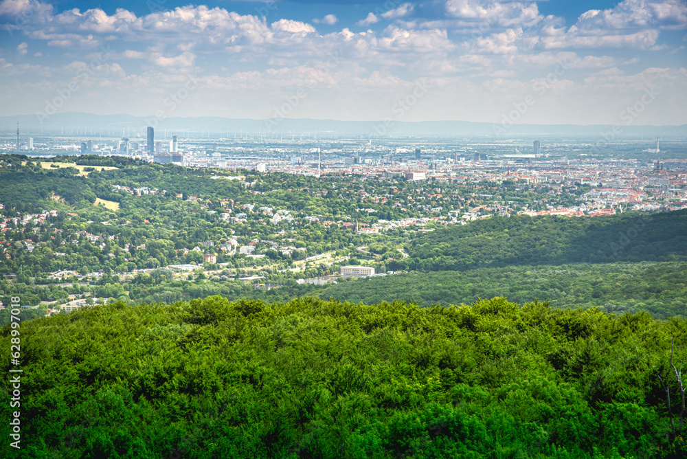 Aerial view on the outskirts of Vienna city in Austria with the beautiful green hills of the Viennese forest and a dramatic sky in the summer 