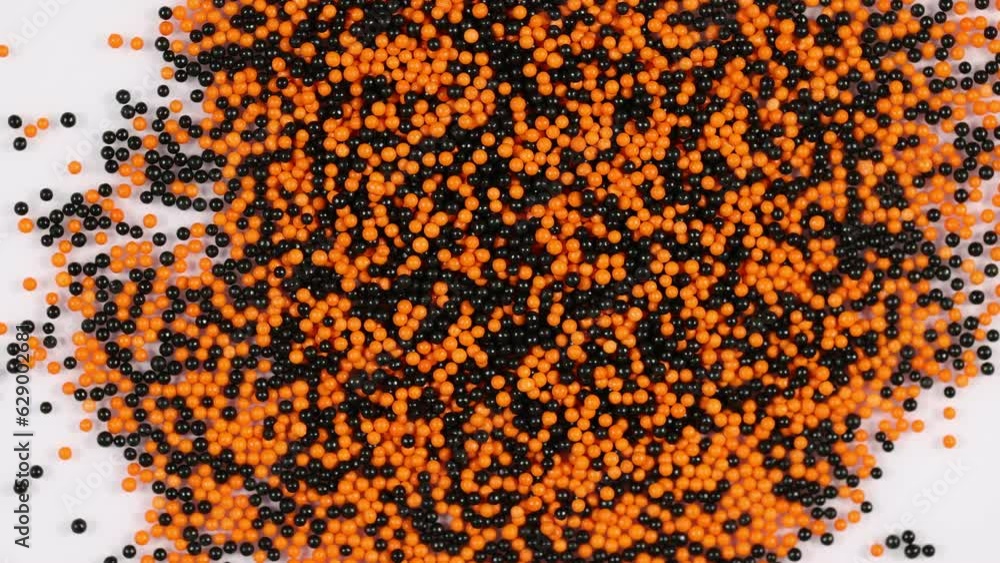 Orange and black candy ball sprinkles spinning clockwise Orange and black candy ball sprinkles spinning clockwise