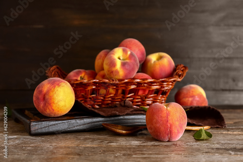 Wicker basket with sweet peaches on wooden background