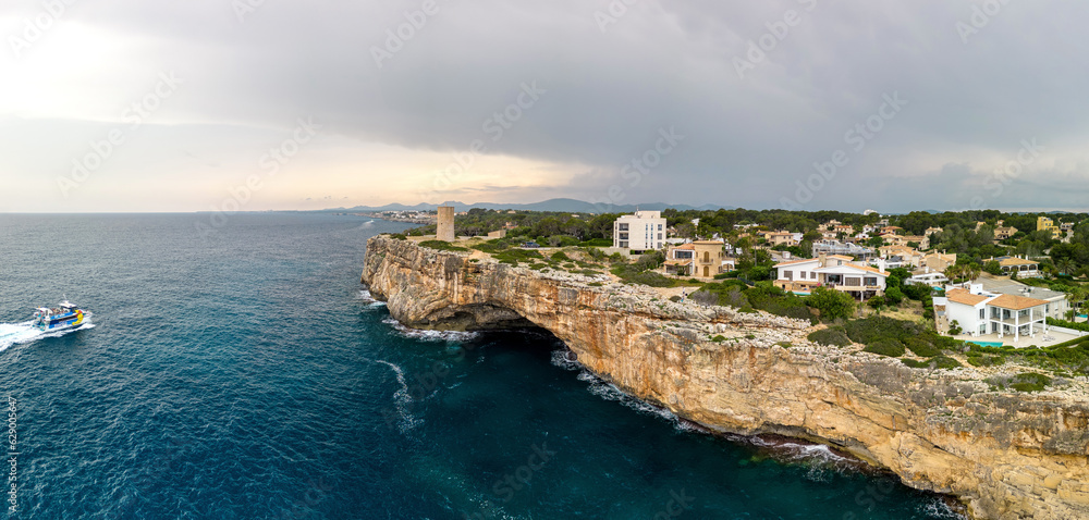 Aerial view of the coastline near Porto Cristo in the spanish island of mallorca, A boat is traveling up the coast near the luxury houses on the cliffs, Porto Cristo Mallorca, mediterranean landscape