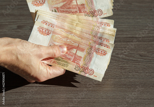 A man is holding a fan of 5000 rubles banknotes in close-up.