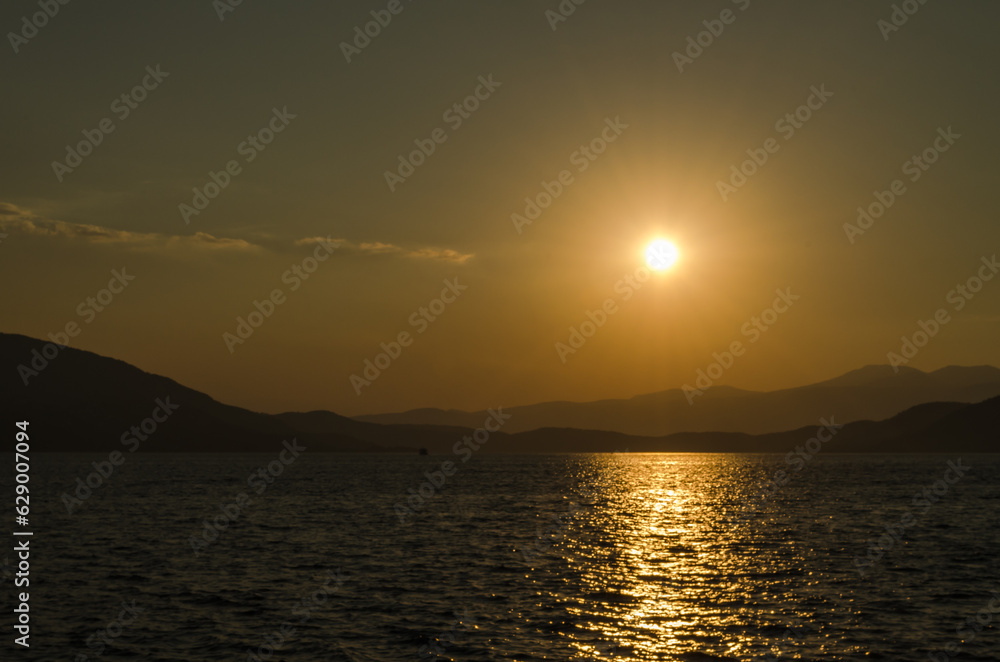 Evia island, Greece - July 01. 2020: Sunset on the island of Evia, Greece. Panoramic view of the sunset on the Greek island of Evia in the Aegean Sea. Evia island, Greece - July 01. 2020: Sunset on the island of Evia, Greece. Panoramic view of the sunset on the Greek island of Evia in the Aegean Sea.