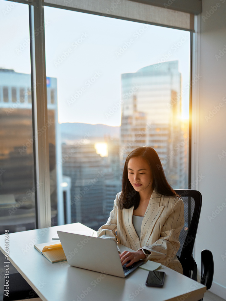 Busy Asian business woman using laptop in company office. Young female digital finance professional worker using computer doing corporate data management sitting at desk, city window view, vertical. Busy Asian business woman using laptop in company office. Young female digital finance professional worker using computer doing corporate data management sitting at desk, city window view, vertical.