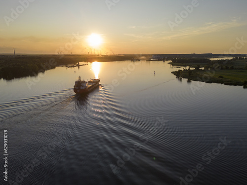 Cargo ship leaving port and strting the journey at sunny morning sunrise