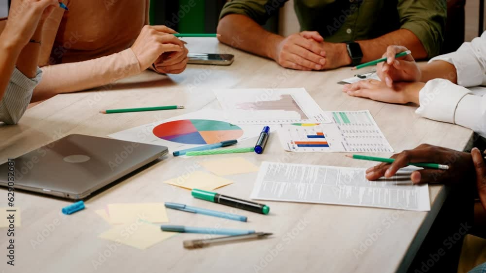 Team of office workers discusses charts and graphs on papers Team of office workers discusses charts and graphs on papers