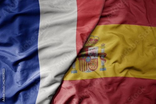 big waving realistic national colorful flag of france and national flag of spain .