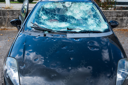 hail damage to car. damaged hood and windshield photo