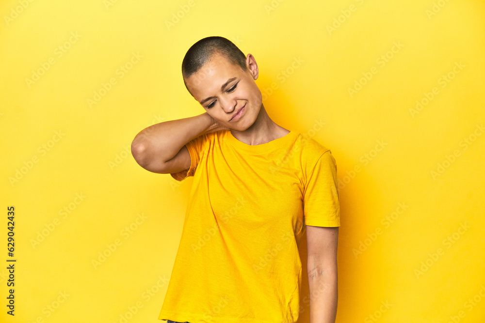 Young woman in yellow tee, yellow studio backdrop suffering neck pain due to sedentary lifestyle. Young woman in yellow tee, yellow studio backdrop suffering neck pain due to sedentary lifestyle.