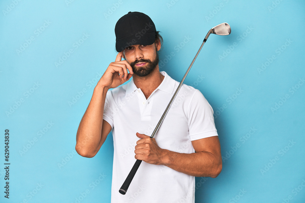 Long-haired golfer with club and hat pointing temple with finger, thinking, focused on a task. Long-haired golfer with club and hat pointing temple with finger, thinking, focused on a task.