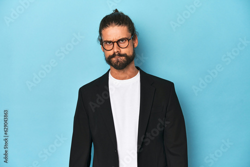 Businessman in suit with eyeglasses and beard confused, feels doubtful and unsure.