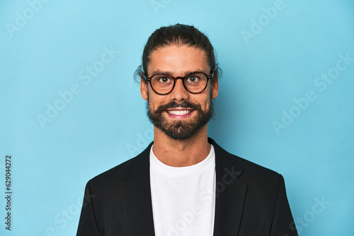 Close-up of bearded businessman in suit against a blue studio background.