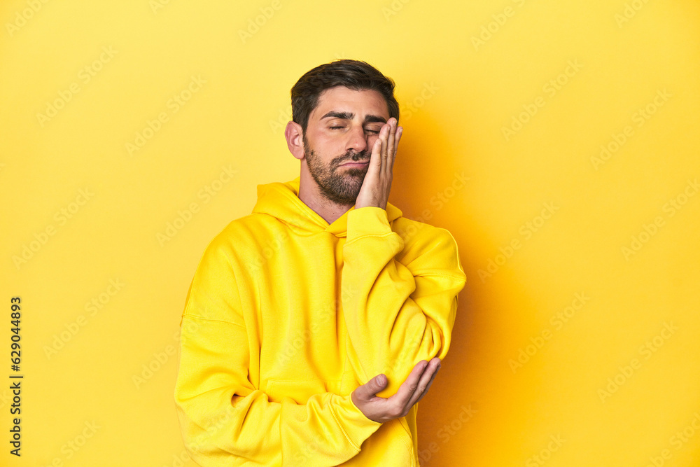 Man in yellow hoodie, monochrome studio backdrop who is bored, fatigued and need a relax day. Man in yellow hoodie, monochrome studio backdrop who is bored, fatigued and need a relax day.