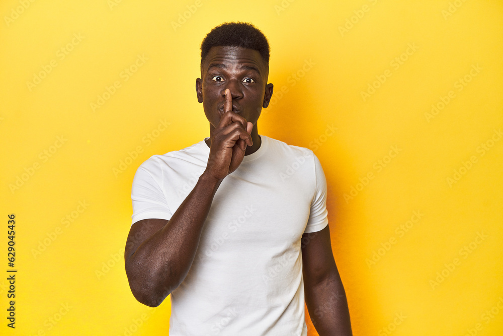 Stylish young African man on vibrant yellow studio background, keeping a secret or asking for silence. Stylish young African man on vibrant yellow studio background, keeping a secret or asking for silence.