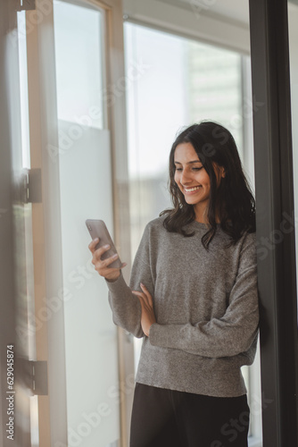 Free Download Smiling indian woman with beautiful hair wearing casual clothes holding mobile phone - GFXLoad