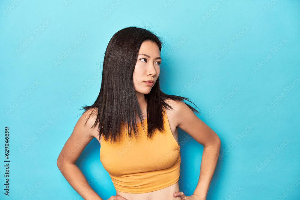 Asian woman in summer yellow top, studio setup, confused, feels doubtful and unsure. Asian woman in summer yellow top, studio setup, confused, feels doubtful and unsure.