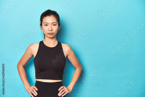 Young Asian sportswoman, studio shot, on blue background.