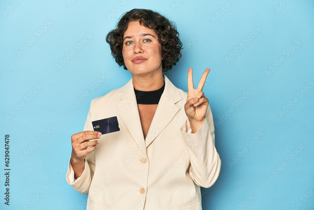 Young woman with credit card, elegant white blazer showing number two with fingers. Young woman with credit card, elegant white blazer showing number two with fingers.