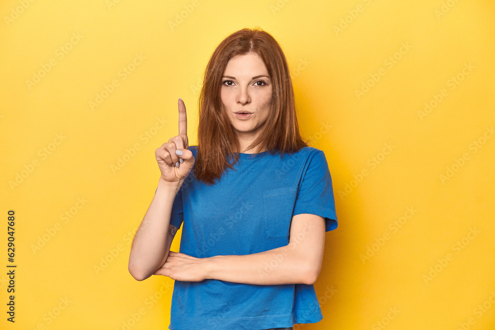 Redhead in blue t-shirt on yellow backdrop having some great idea, concept of creativity. Redhead in blue t-shirt on yellow backdrop having some great idea, concept of creativity.