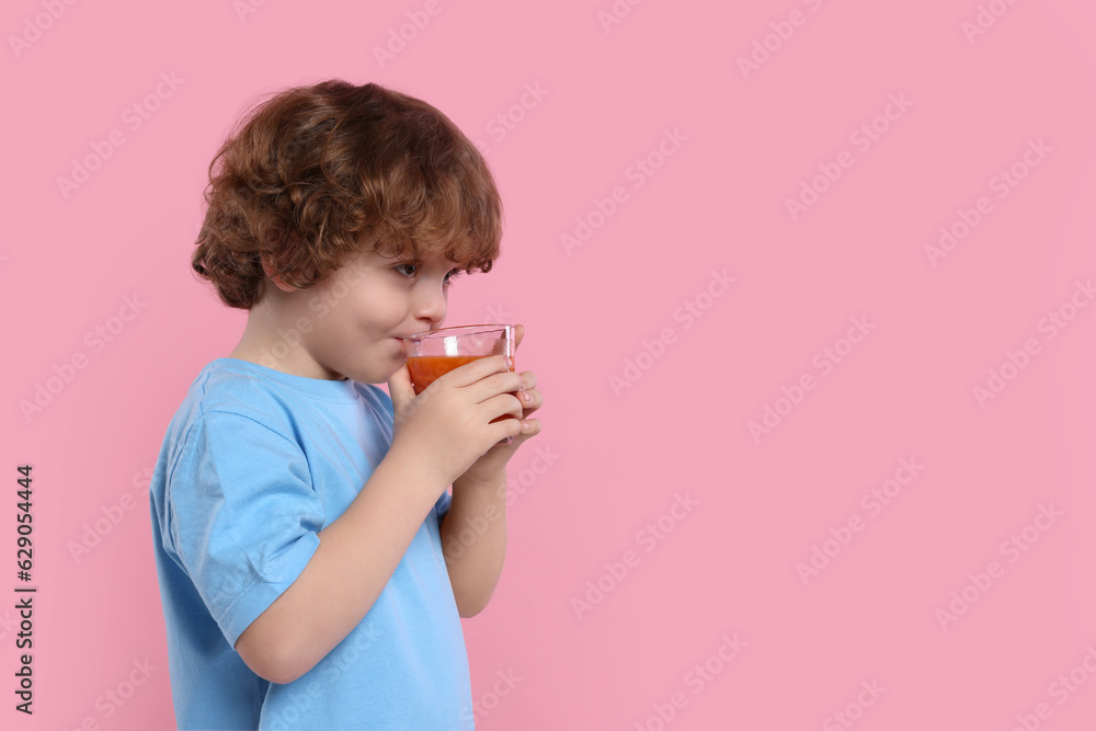 Cute little boy drinking fresh juice on pink background, space for text Cute little boy drinking fresh juice on pink background, space for text