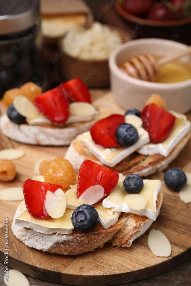 Tasty sandwiches with brie cheese, fresh berries and almond flakes on table Tasty sandwiches with brie cheese, fresh berries and almond flakes on table