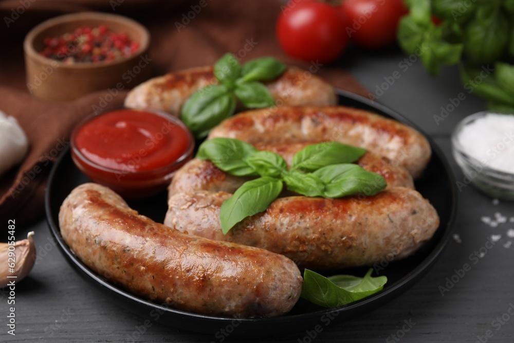 Tasty homemade sausages, ketchup and basil leaves on grey wooden table, closeup Tasty homemade sausages, ketchup and basil leaves on grey wooden table, closeup