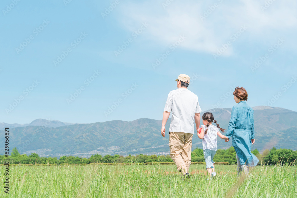 春・夏に公園・草原を歩く家族・ファミリーの後ろ姿（子供・両親・移住・田舎暮らし）
