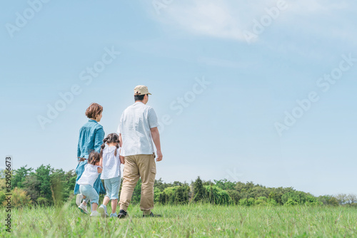 春・夏に公園・草原を歩く家族・ファミリーの後ろ姿（子供・両親・移住・田舎暮らし） 