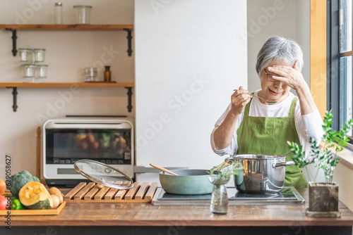 家のキッチンで料理を作るアジア人のシニア・高齢者女性（認知症・悩む）
