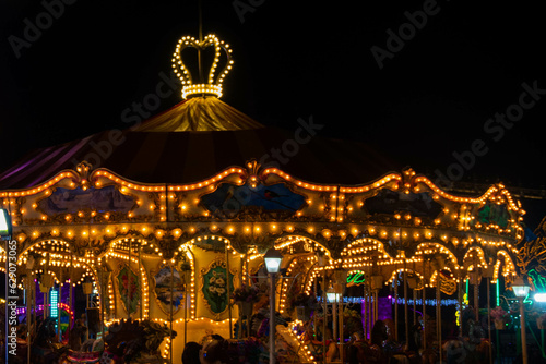 Night shot of the carrousel, with its yellow lights on.