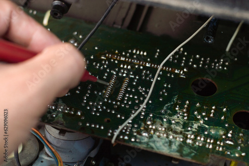 Repairman repairing electronic circuit board with red pen, close-up