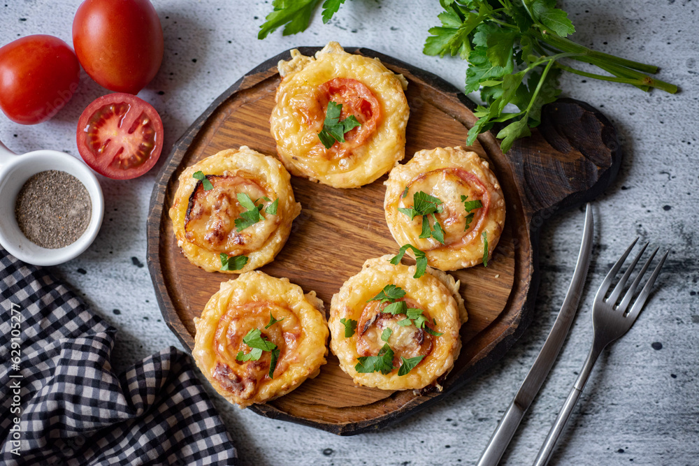 Healthy snack: mini pizza with cheese, tomatoes, fresh herbs and salami on a wooden board on a gray background. View from above. Mini pizza for lunch for the whole family Healthy snack: mini pizza with cheese, tomatoes, fresh herbs and salami on a wooden board on a gray background. View from above. Mini pizza for lunch for the whole family