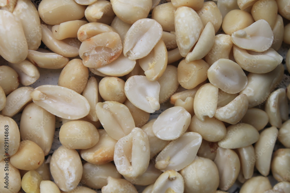 Raw peanuts without skin in a bowl and on a wooden table