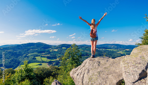 Happy woman standing on cliff, Morvan in France- Travel, freedom, achievement concept