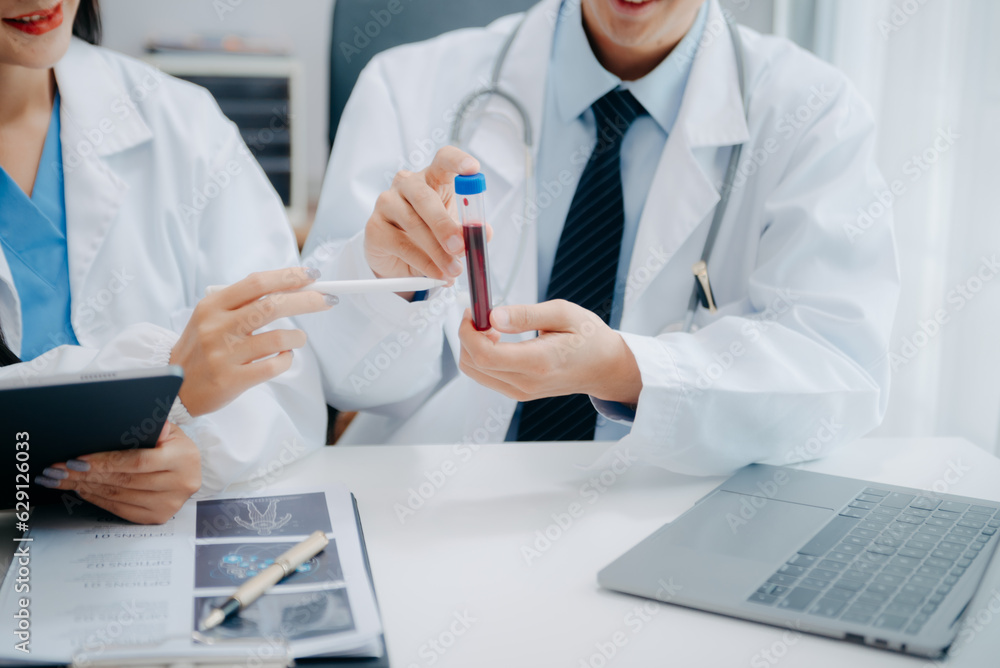 Medical team having a meeting with doctors in white lab coats and surgical scrubs seated at a table discussing a patients working online using computers in the medical industry. Medical team having a meeting with doctors in white lab coats and surgical scrubs seated at a table discussing a patients working online using computers in the medical industry.