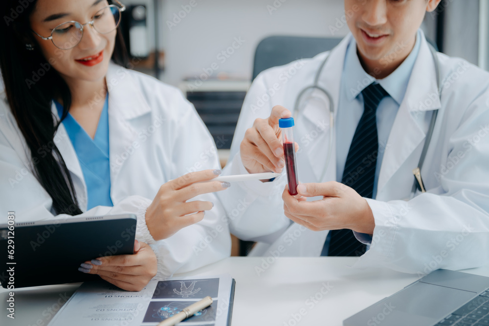 Medical team having a meeting with doctors in white lab coats and surgical scrubs seated at a table discussing a patients working online using computers in the medical industry. Medical team having a meeting with doctors in white lab coats and surgical scrubs seated at a table discussing a patients working online using computers in the medical industry.