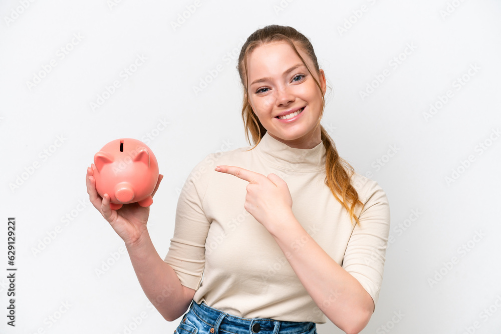 Young caucasian girl holding a piggybank isolated on white background and pointing it Young caucasian girl holding a piggybank isolated on white background and pointing it