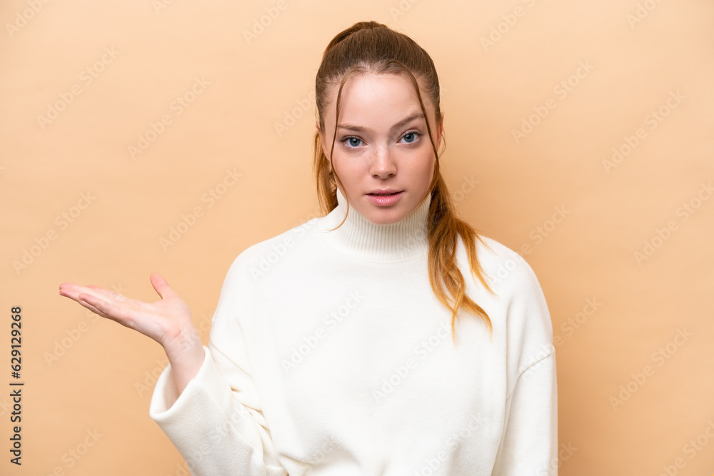 Young caucasian woman isolated on beige background making doubts gesture Young caucasian woman isolated on beige background making doubts gesture