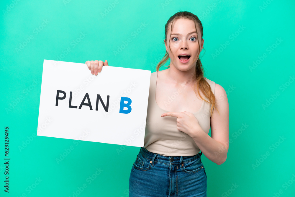 Young caucasian woman isolated on green background holding a placard with the message PLAN B with surprised expression Young caucasian woman isolated on green background holding a placard with the message PLAN B with surprised expression