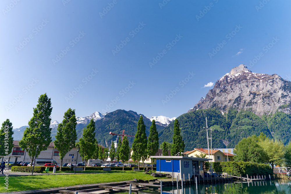 Lakeshore with pier and marina at Swiss village of Flüelen on a sunny spring morning with beautiful mountain panorama in the background. Photo taken May 22nd, 2023, Flüelen, Canton Uri, Switzerland.