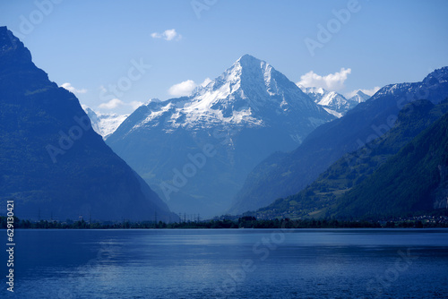 Scenic mountain panorama with Lake Lucerne in the foreground and Swiss village Flüelen in the background on a sunny spring day. Photo taken May 22nd, 2023, Lake Lucerne, Switzerland. © Michael Derrer Fuchs